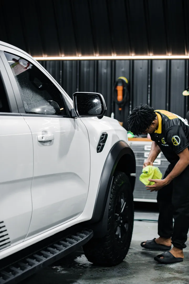 Supreme Details detailer wiping down a white pickup truck in the studio