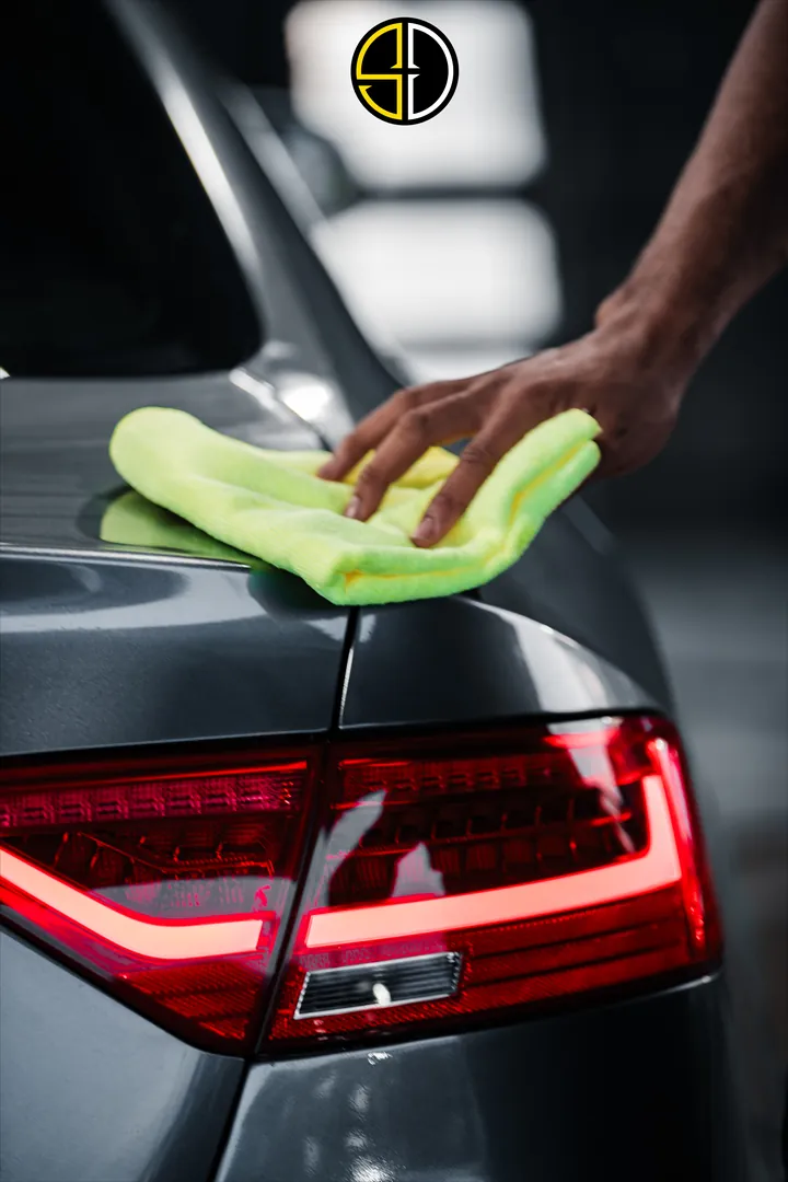 Microfibre towel buffing the glossy grey paint above an Audi's tail light